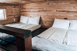 A cabin-style room with wooden walls, a bunk bed, and a window.