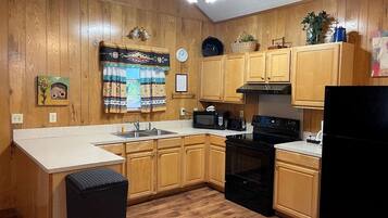 A kitchen with wooden cabinets, a black refrigerator, a microwave, and a stove.