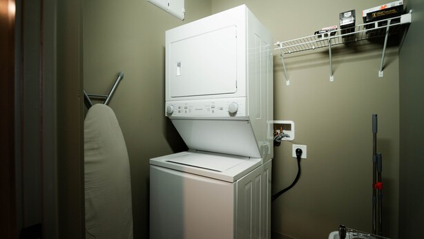 A laundry area with a washing machine, dryer, and a shelf with cleaning supplies.