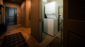 A laundry room with a washer and dryer, a door, and a carpeted floor.