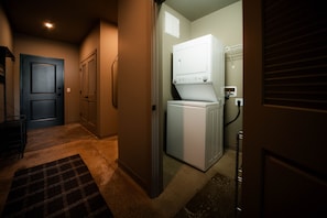 A laundry room with a washer and dryer, a door, and a carpeted floor.