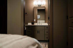 A hotel bathroom with a mirror, sink, and towel rack. - The Shumaker | Unit 103 | Modern Lancaster Apt (Lancaster)
