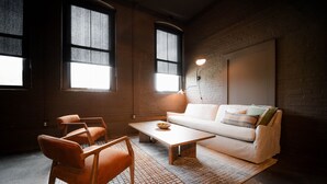 Un salon moderne avec un canapé, des fauteuils, une table basse et de grandes fenêtres.