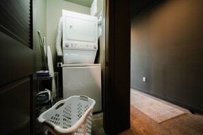A laundry room with a washer and dryer, a basket, and a carpeted floor.