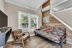 A room with a sofa, a chair, a TV, and a staircase. - Rustic Cabin Retreat with Loft, Fire Pit & Community Pool in Branson, Missouri (Branson)