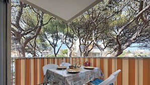 A balcony with a table set for dining, chairs, and a view of trees and buildings. - The Oasis Family T3Clim: Terraces, Parks, and Beaches Within Walking Distance (Fréjus)