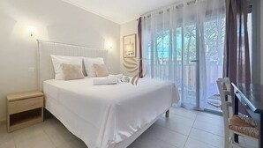 A bedroom with a bed, bedside table, and a view of the outdoors. - The Oasis Family T3Clim: Terraces, Parks, and Beaches Within Walking Distance (Fréjus)