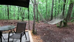 Una cadira d'hamaca a la selva, una taula amb caires, i una zona coberta.