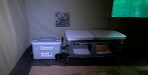 A room with a grey storage unit, a small table, and a green curtain.