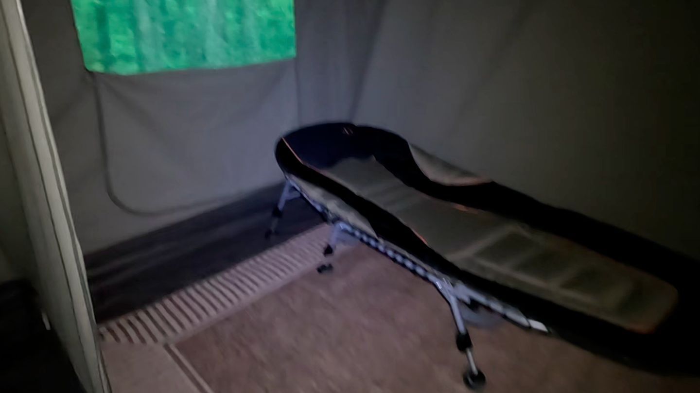Un lit simple dans une chambre avec une fenêtre, une porte et un sol recouvert de moquette.
