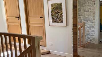 Una stanza con porte in legno, un quadro incorniciato appeso al muro, un muro in pietra e una scala di legno.