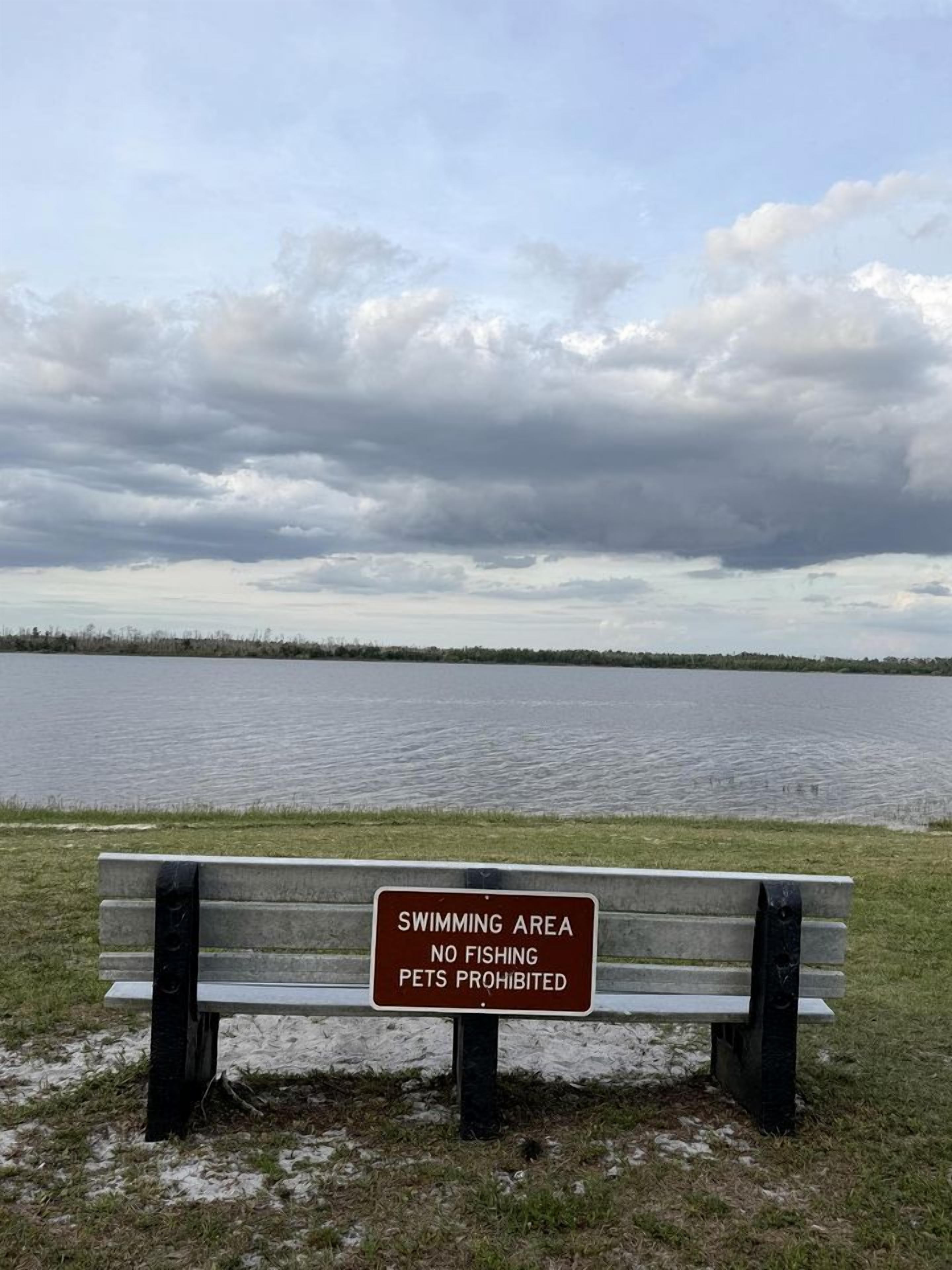 A bench with a sign indicating a swimming area where fishing and pets are prohibited.