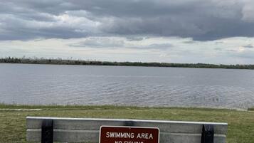 A bench with a sign indicating a swimming area where fishing and pets are prohibited.