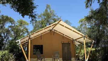 A single-story tent with a pitched roof, a door, and two chairs outside.
