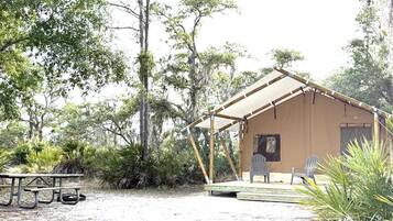 A rustic wooden cabin with a covered porch, a picnic table, and two Adirondack chairs.