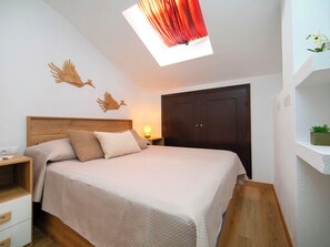 Een slaapkamer met een houten hoofdbord, een bed met beige beddengoed, een nachtkastje met een lamp en een garderobe.