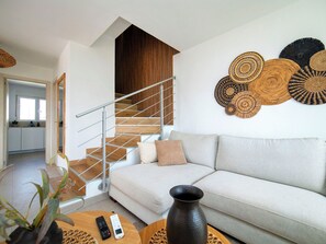 Ein modernes Wohnzimmer mit Treppe, einer Couch, einem Couchtisch und Wandbildern.