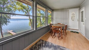 A room with a wooden table and chairs, large windows with a view of a lake, and a door with an ornate design. - The Cove on Lake Carlos (Carlos Township)