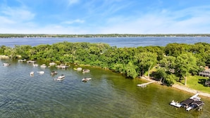 A lake with boats, a dock, and a building with a covered area. - The Cove on Lake Carlos (Carlos Township)