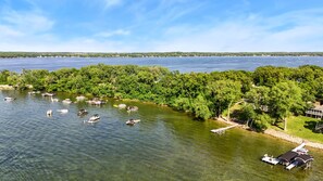 A lake with boats, a dock, and a building with a covered area. - The Cove on Lake Carlos (Carlos Township)