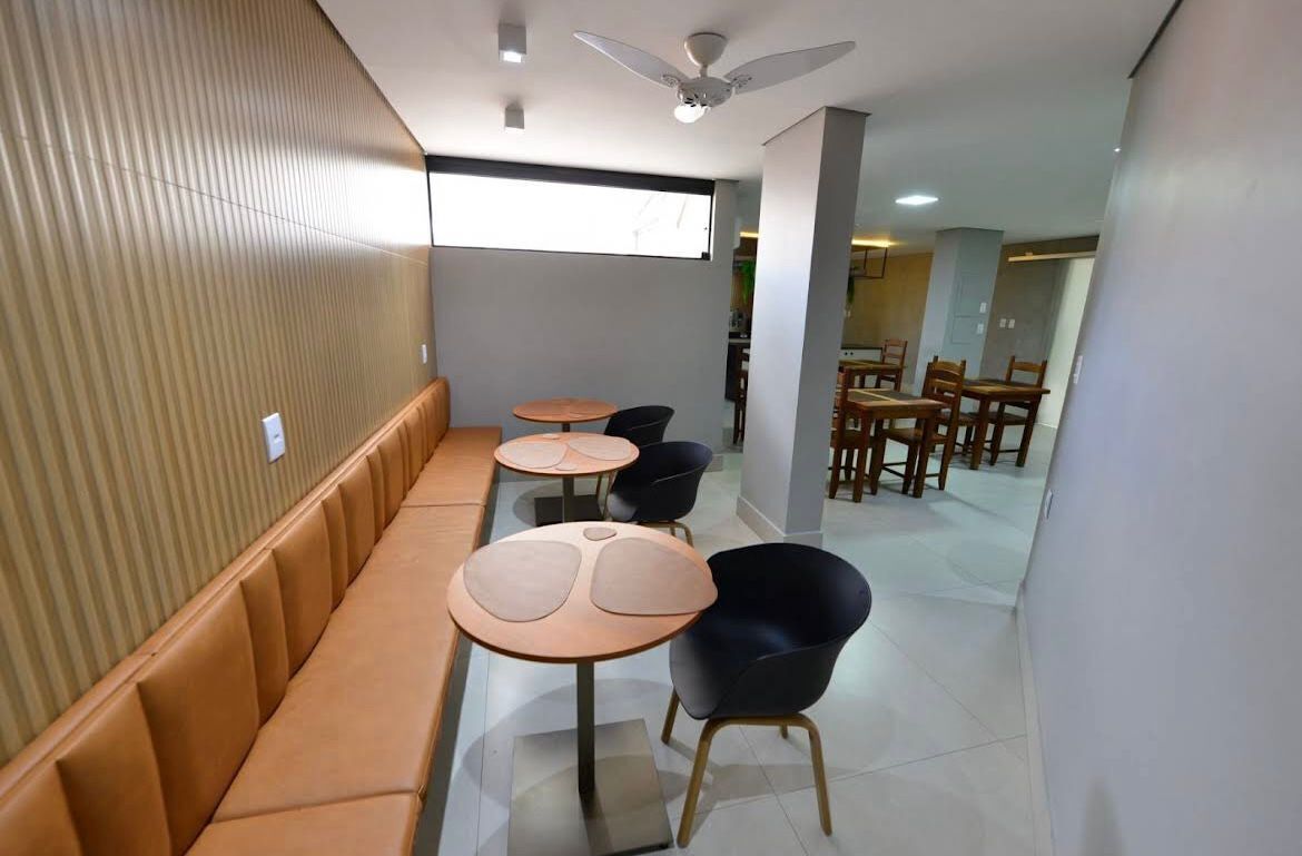 A modern interior with a long bench seating area, round tables, and chairs.