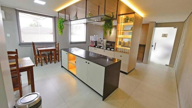 A modern kitchen with a central island, wooden chairs, a dining table, and a refrigerator.