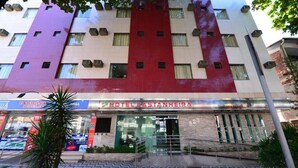 A multi-story hotel with a prominent red and beige facade, a visible entrance with a staircase, and a sign for 'Hotel Castanhaira.'