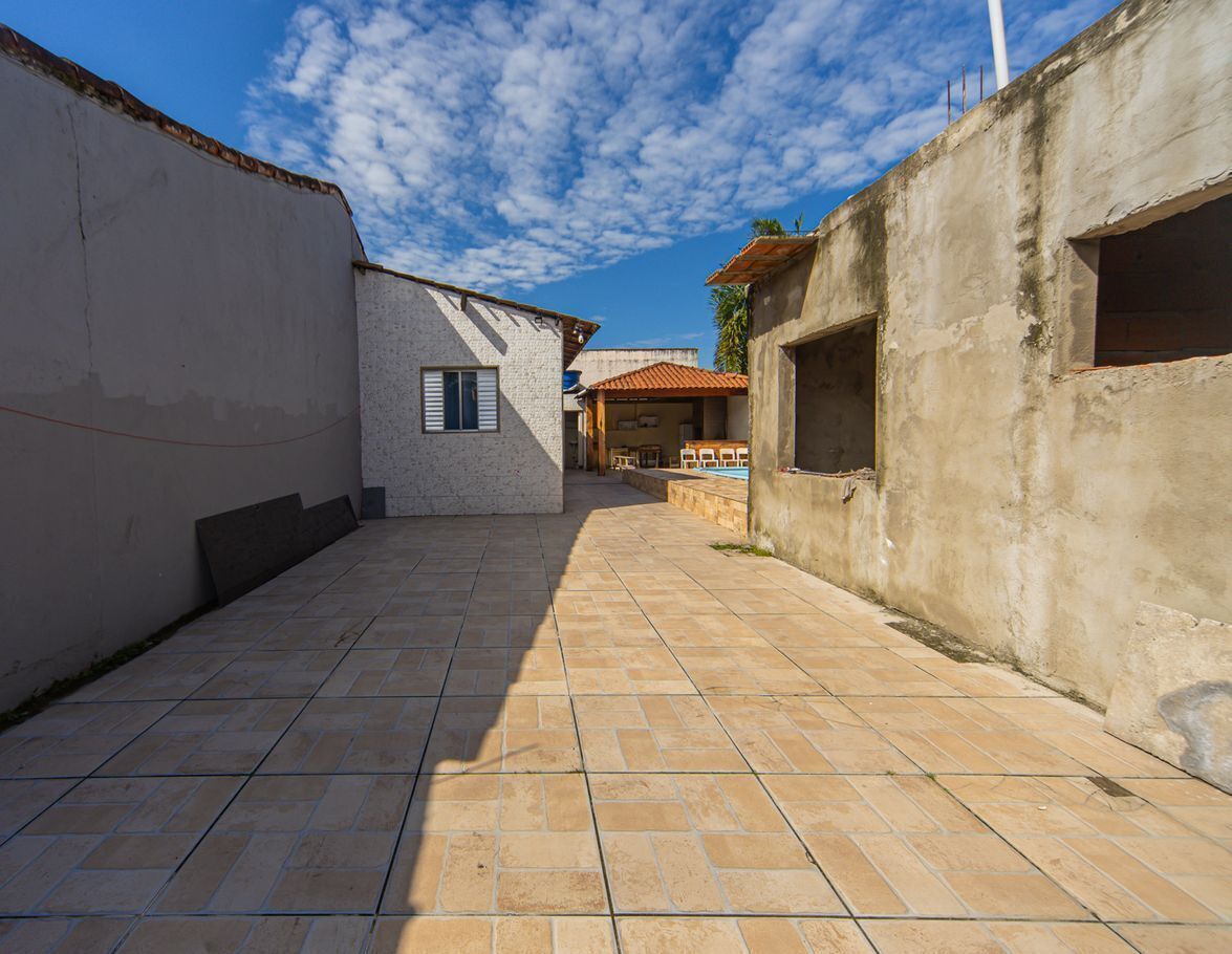 A courtyard with a tiled floor, a building with a window, and a partially constructed wall.