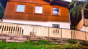 Une cabane en bois avec un balcon, une fenêtre et une porte.
