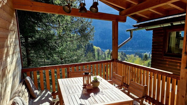 Une terrasse en bois avec une table et des chaises, offrant une vue sur un paysage montagneux.