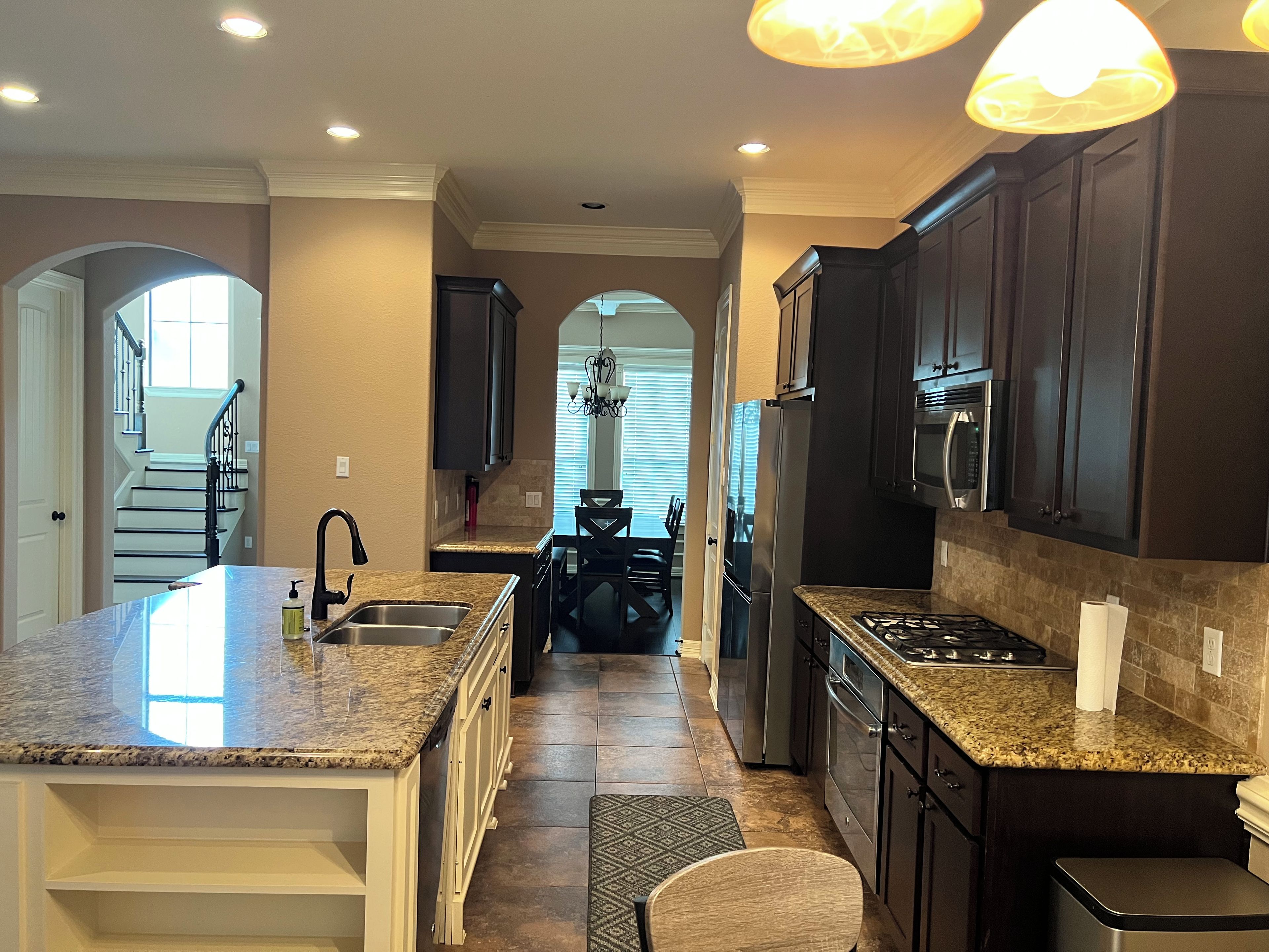 A modern kitchen with granite countertops, stainless steel appliances, and dark cabinetry.