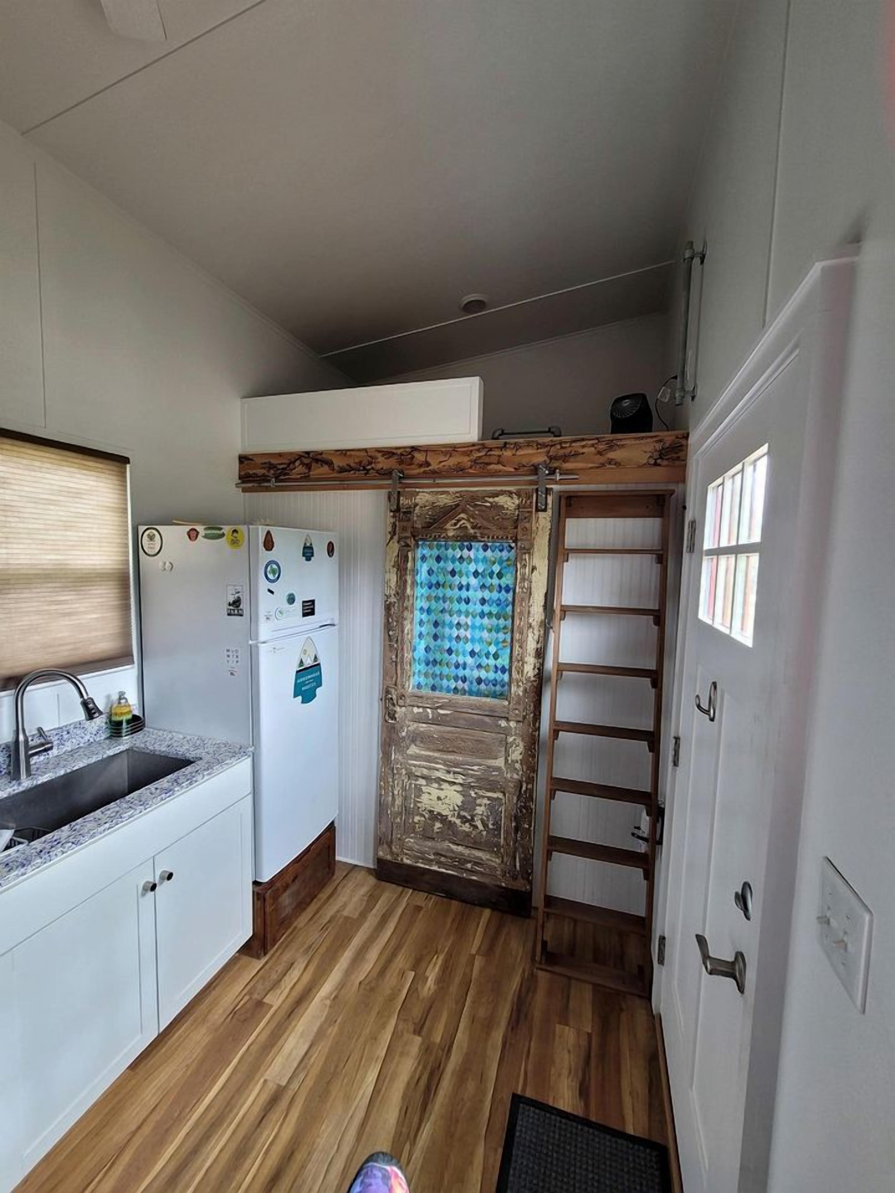 Eine kleine Küche mit Kühlschrank, Spüle und Holzboden.