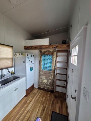 Eine kleine Küche mit Kühlschrank, Spüle und Holzboden.