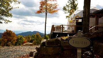 A sign labeled 'Truth' in front of a building with a stone wall and a view of mountains.