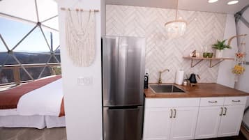 A modern kitchen with a stainless steel refrigerator, wooden countertop, and white cabinetry.