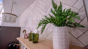 Een houten plank met een potplantvaren, twee groene glazen bekers en een decoratieve zwaan.