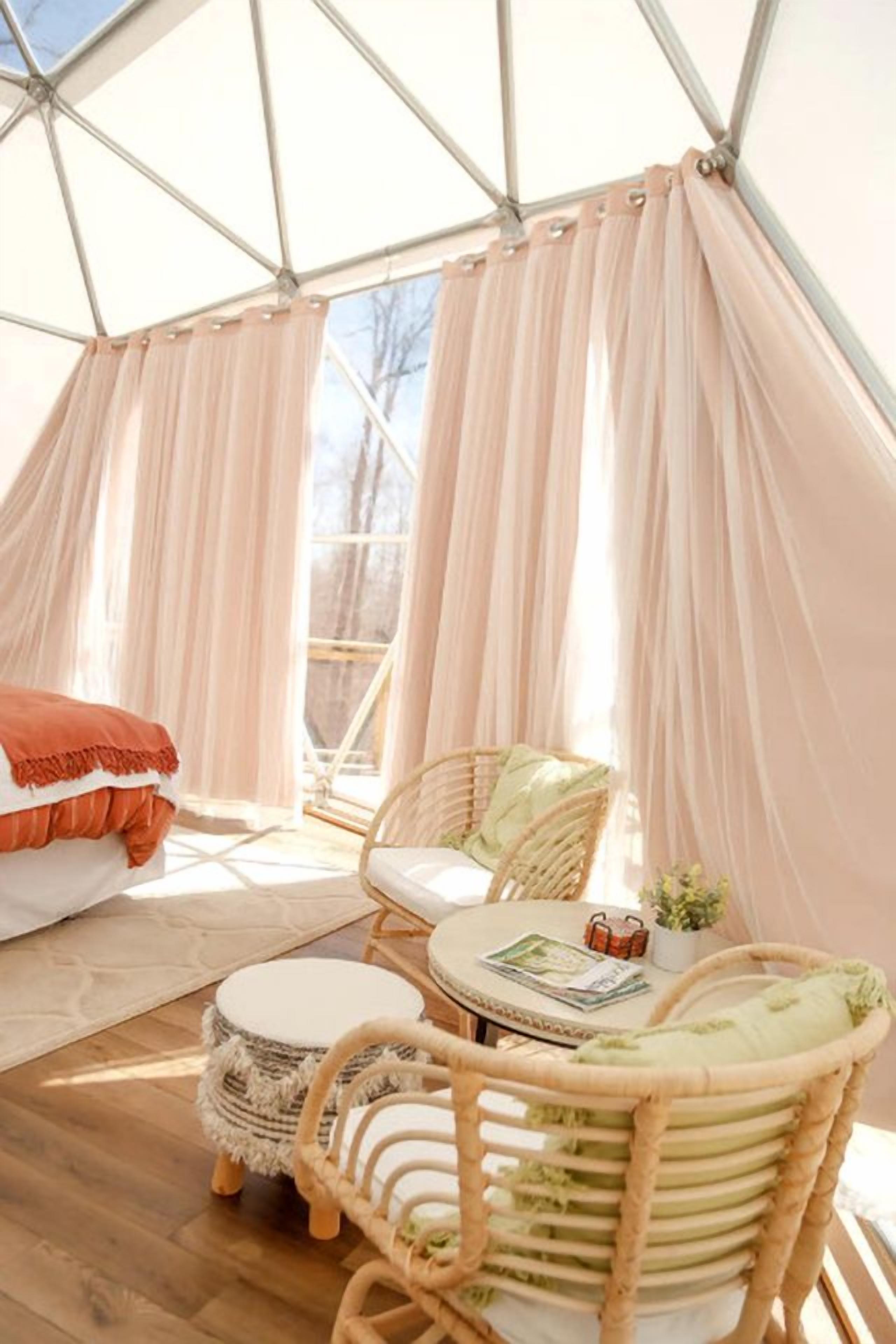 A cozy tent with a round table, wicker chairs, and a cushioned bench.