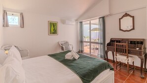 Habitación de hotel con cama, escritorio, silla, ventana con cortinas y vistas al exterior.