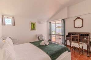 Ein Hotelzimmer mit Bett, Schreibtisch, Stuhl, einem Fenster mit Vorhängen und Blick ins Freie.