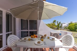 A table with breakfast items, an umbrella, and a view of the surrounding area. - #369 One-Bedroom Apartment in Moinho (Albufeira)