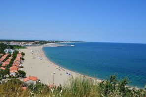 A coastal beach with rows of houses and a clear blue sky.