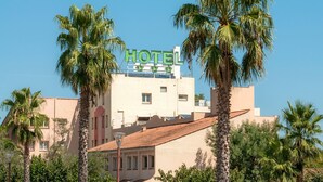 Un hotel con un cartello, palme e un cielo azzurro limpido.