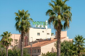 A hotel with a sign, palm trees, and a clear blue sky.