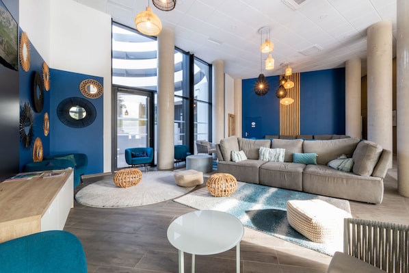 Een moderne woonkamer met een bank, een rond tafel en rieten poufs.