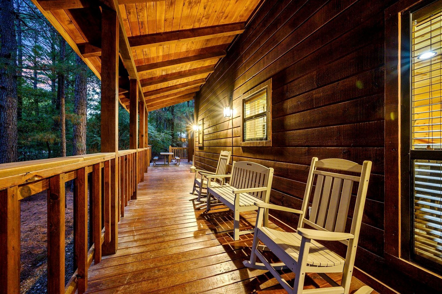 A wooden deck with benches, a table, and a window with blinds.