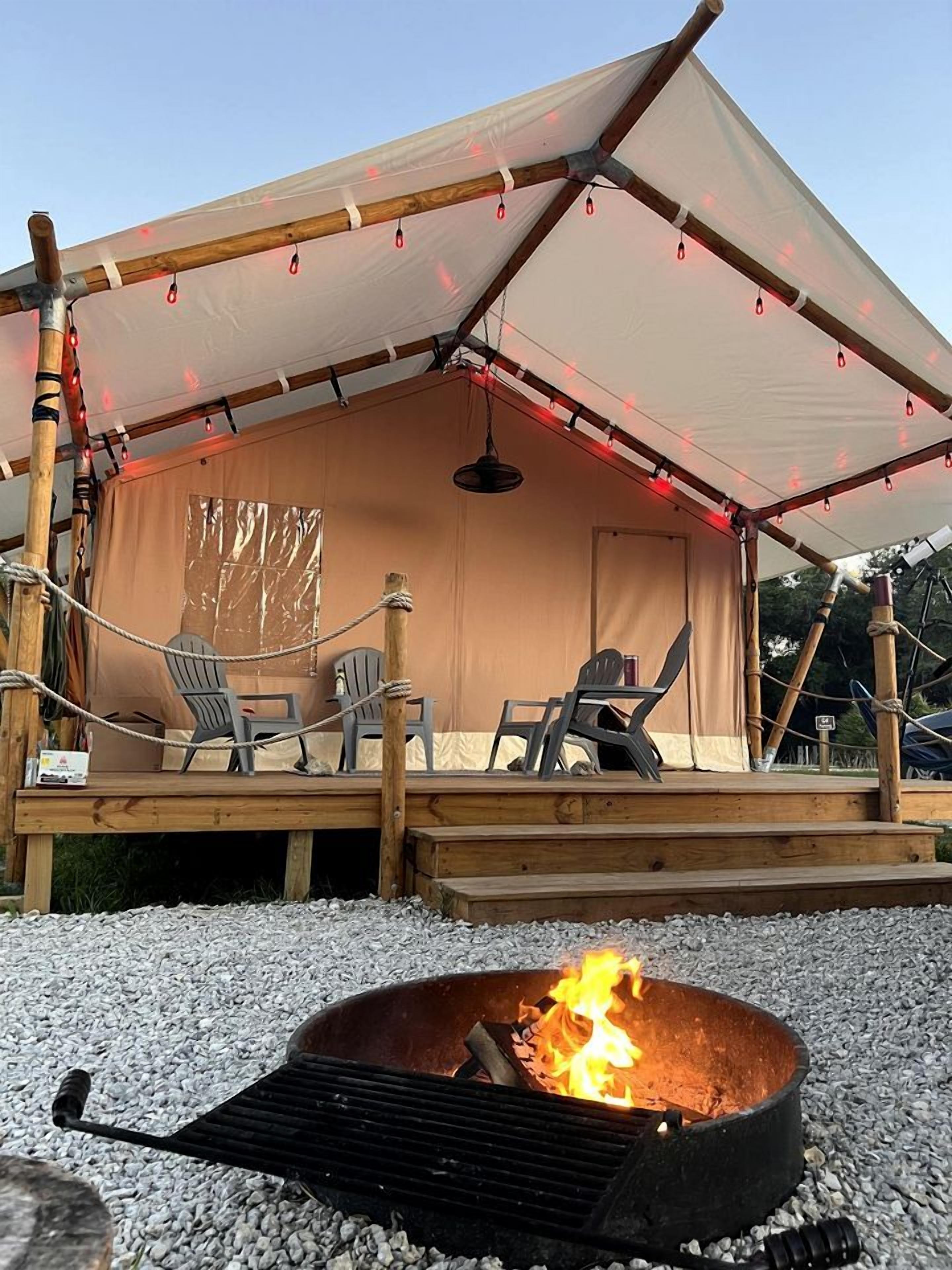 A covered outdoor seating area with chairs and a fire pit.