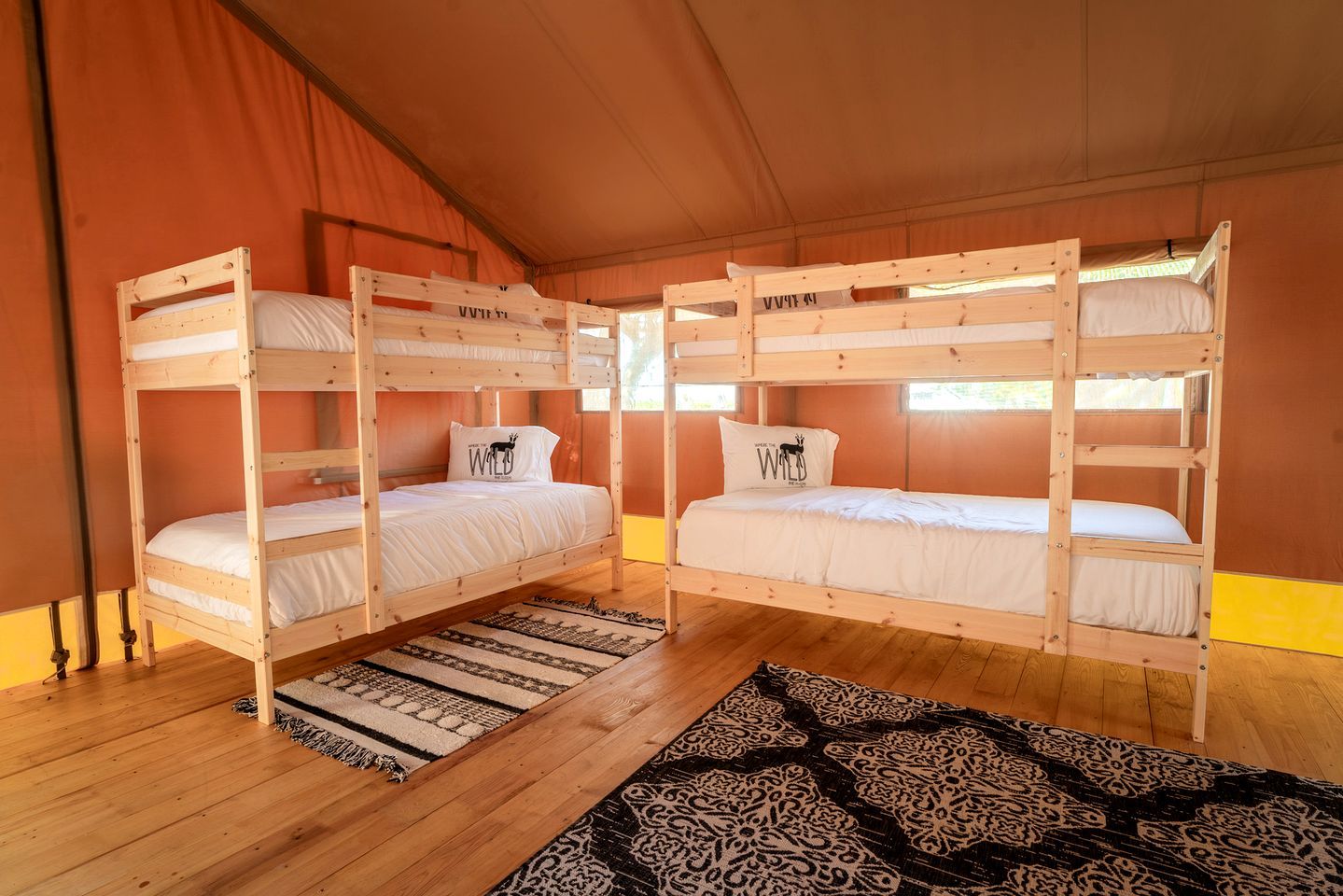 A bunk bed room with a patterned rug and a window.