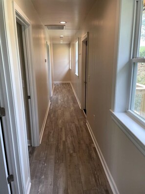 A hallway with wooden flooring, white walls, and a window on the right. - Incredible Waterfront Cabin for a Peaceful Family Getaway near Purlear, North Carolina (Purlear)
