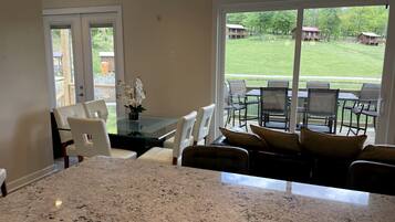 A kitchen with granite countertops, a dining area with white chairs, and a large glass door leading to a patio with outdoor furniture.