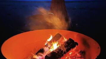 A campfire at night with a clear view of the sky and distant mountains.